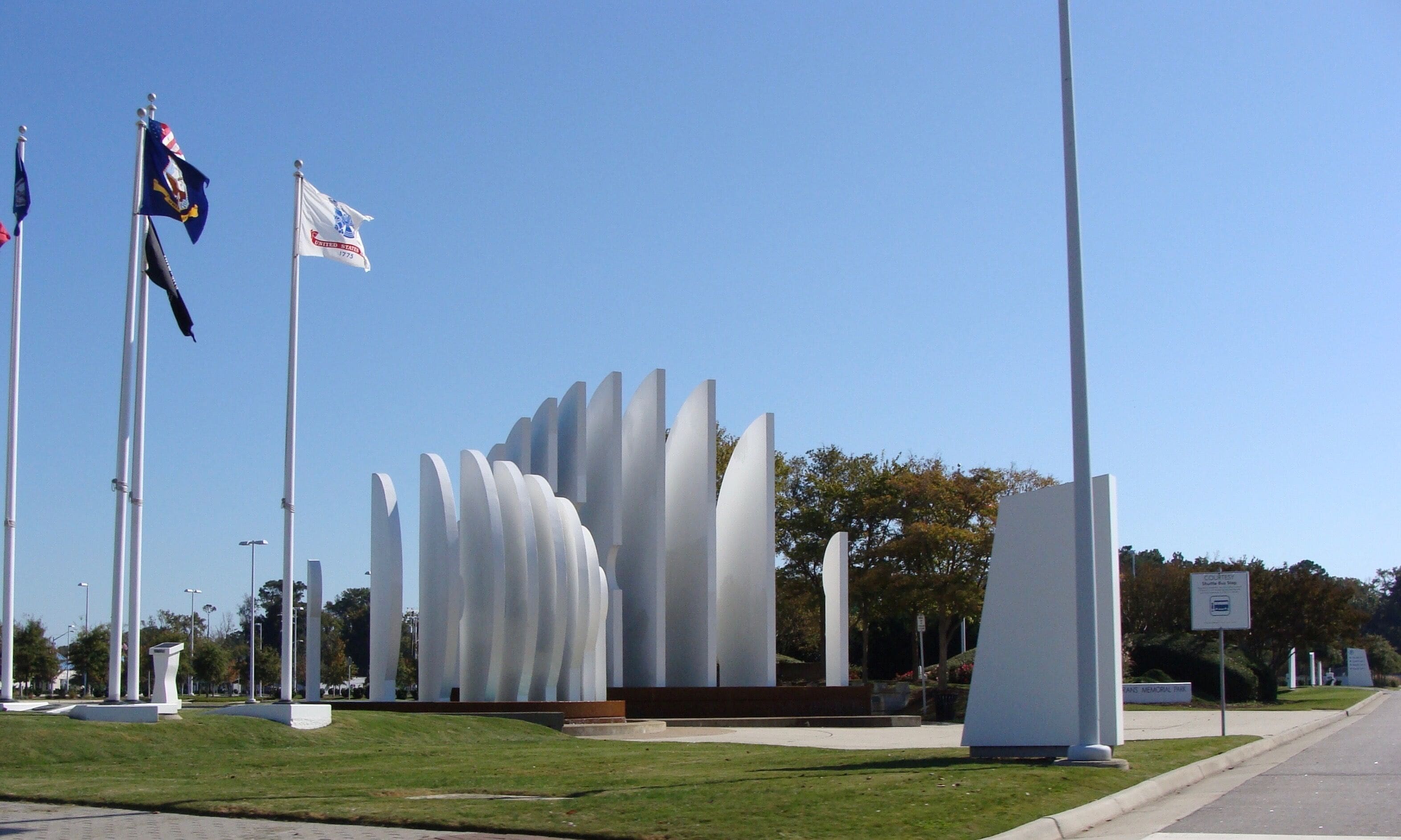 A memorial with tall, white columns and flags on flagpoles.