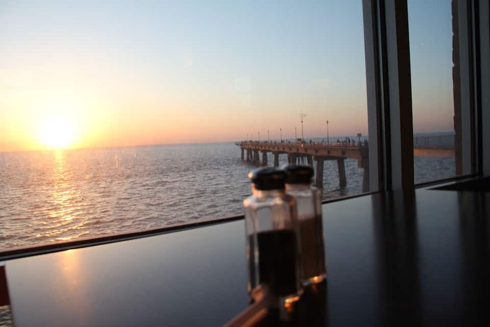 A sunset over the ocean with a pier extending into the water.