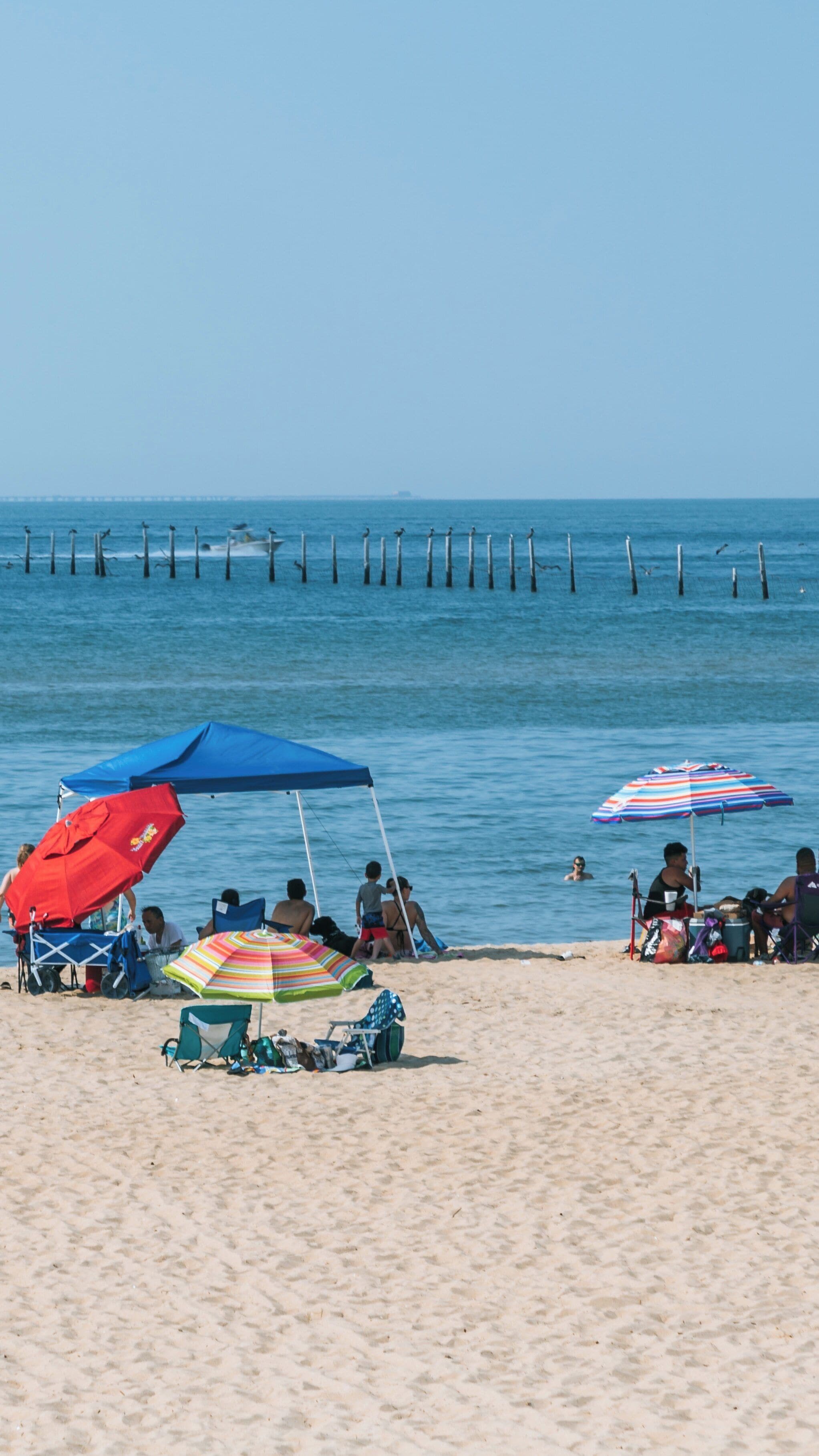 Sunny day at First Landing State Park beach in Northeast Virginia Beach, where families enjoy the water and sand with colorful umbrellas and chairs