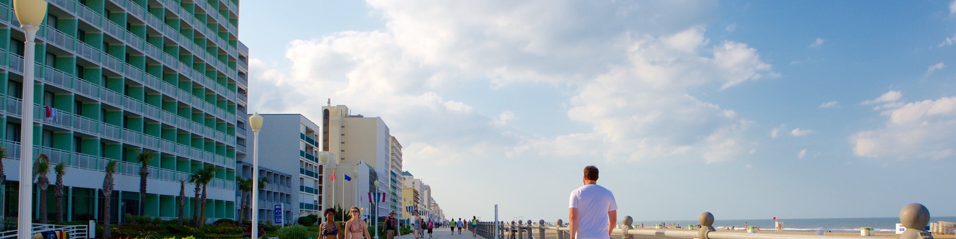 Um calçadão costeiro com praia, fileira de hotéis e céu limpo.