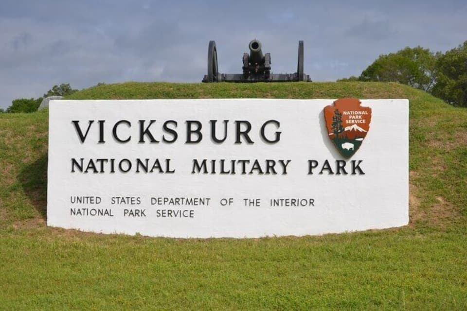 A sign for Vicksburg National Military Park with a cannon in the background.