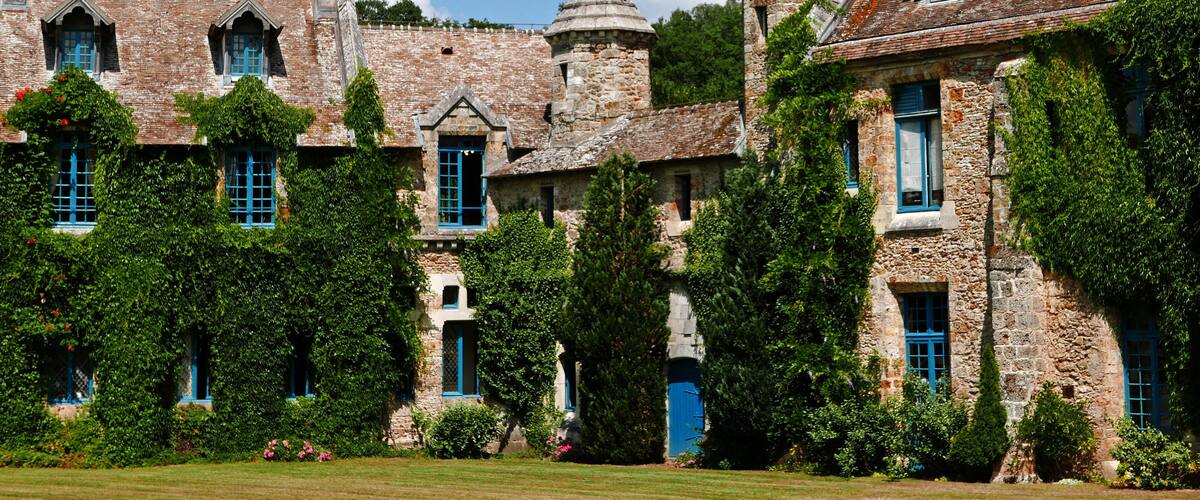A historic stone building with blue shutters and ivy-covered walls.