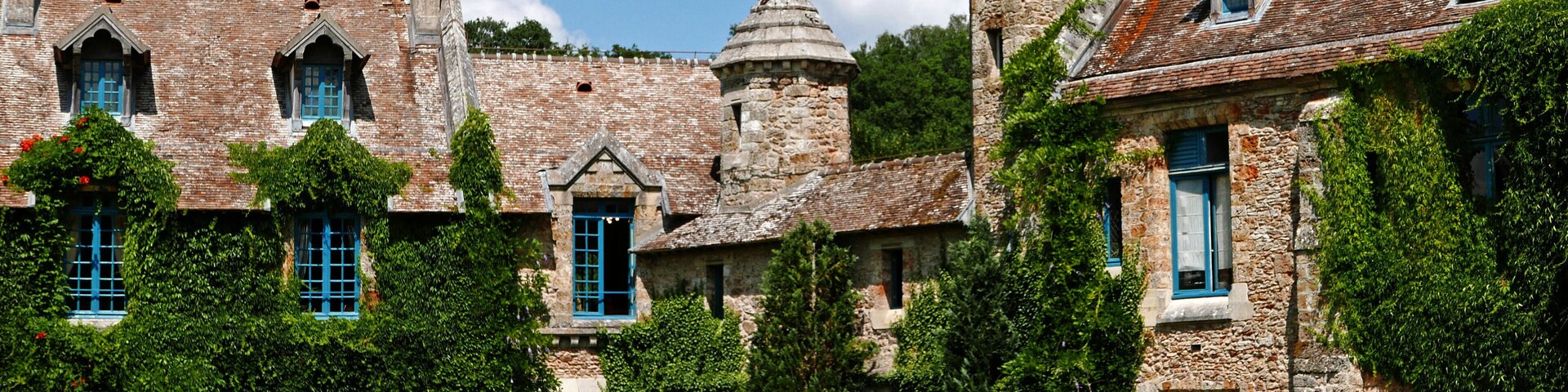 A historic stone building with blue shutters and ivy-covered walls.