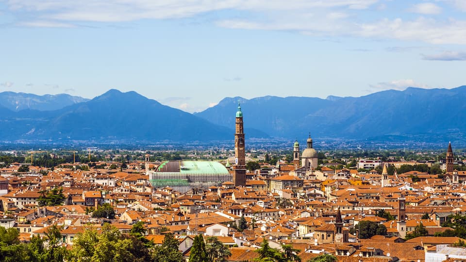 A cityscape with a prominent tower, domed buildings, and mountains in the background.