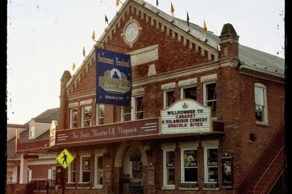A historic theater with a summer festival banner and a sign welcoming visitors to a comedy show.