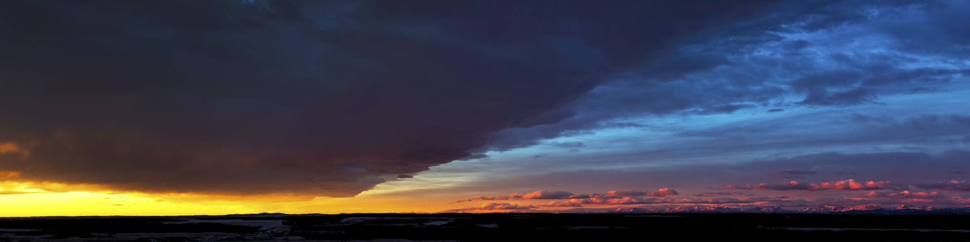 A dramatic sky with a mix of dark clouds and a sunset.