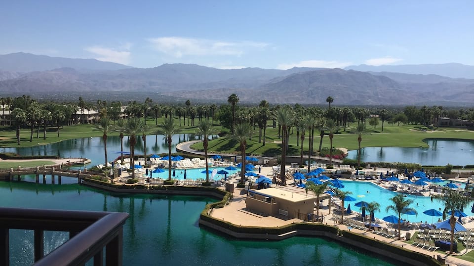 A resort with multiple swimming pools, palm trees, and a golf course.