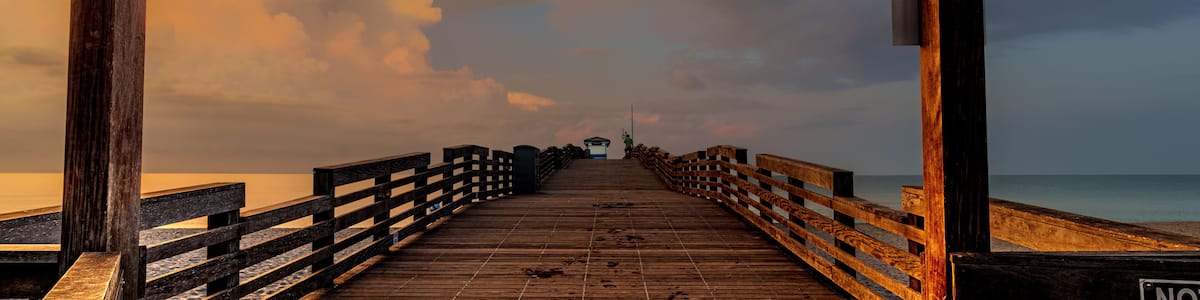 Une jetée en bois, sur laquelle on peut lire l’inscription « Venice Fishing Pier », avec des palmiers en arrière-plan.
