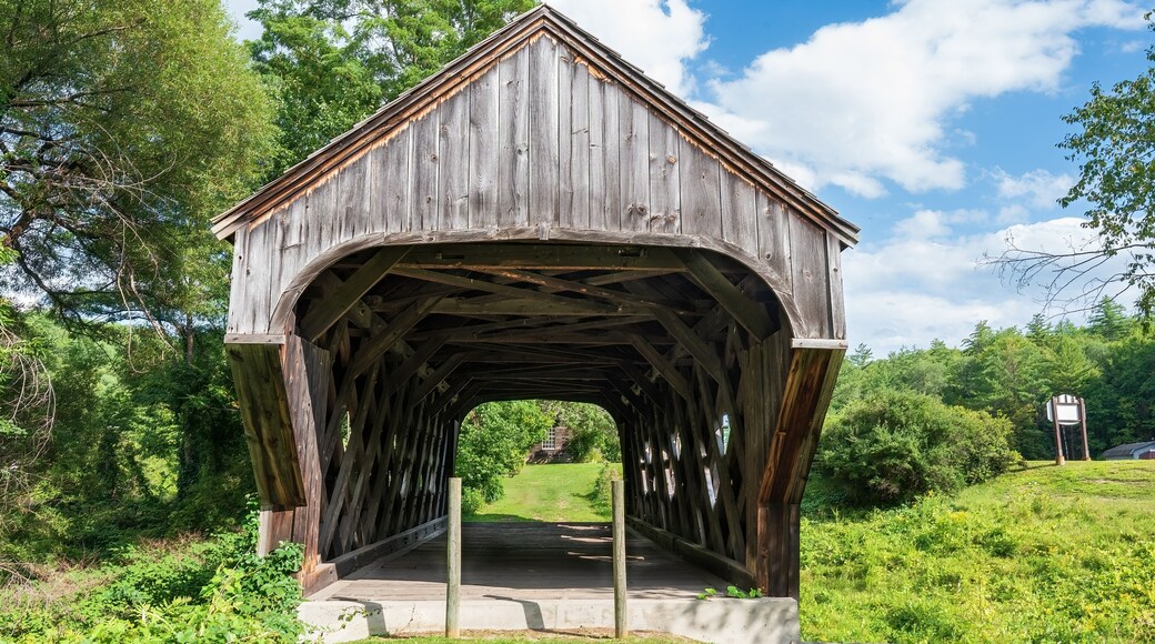 East end of the Baltimore covered bridge is an old wooden bridge located in Springfield Vermont with dark weathered wood located next to the Eureka one-room schoolhouse. Summer day in full sun.