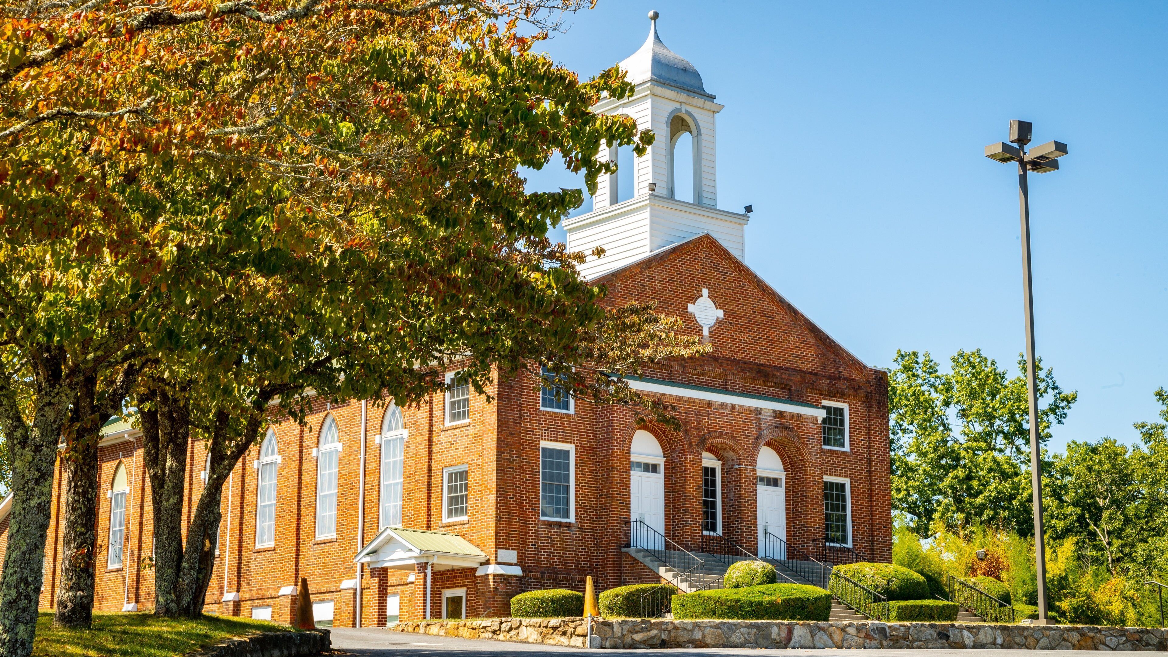 A brick church with a bell tower and a covered entrance.