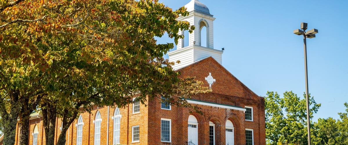 A brick church with a bell tower and a covered entrance.