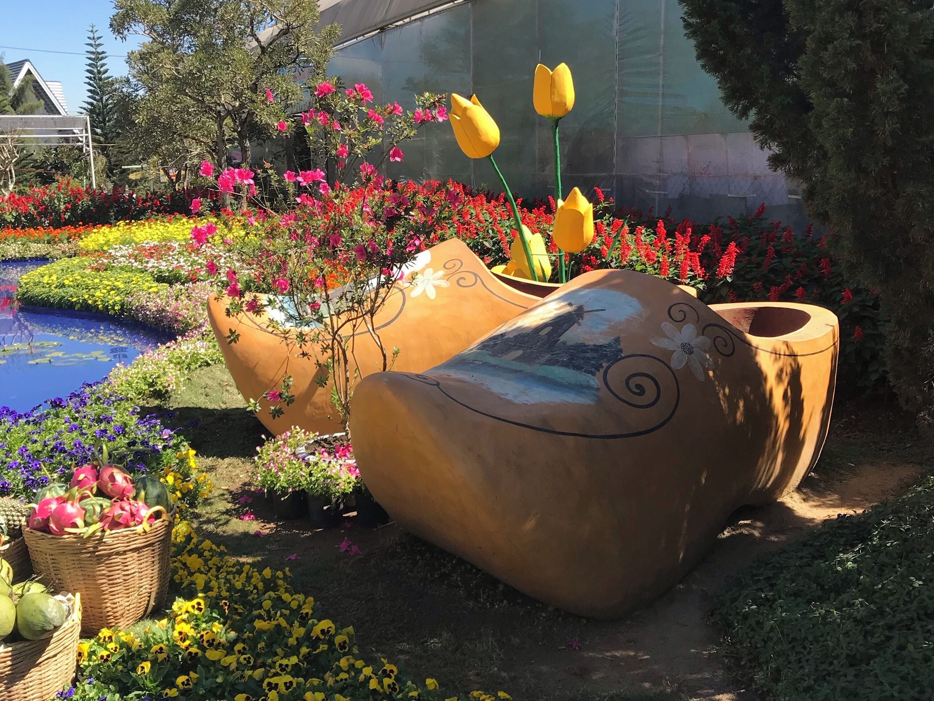 A garden with large terracotta pots, a pond, and colorful flowers.