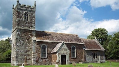 A historic church with a tall tower and a graveyard in front.