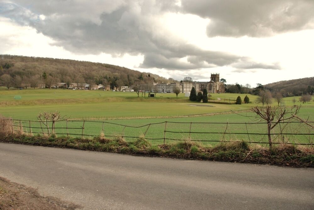 A rural landscape with a castle, green fields, and a road.