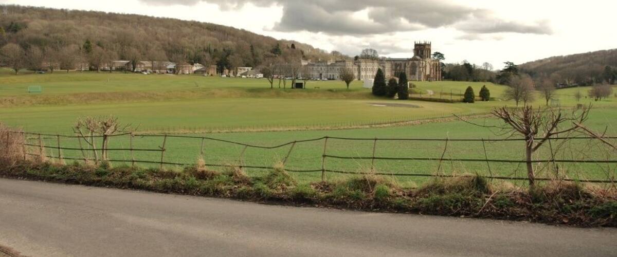 A rural landscape with a castle, green fields, and a road.