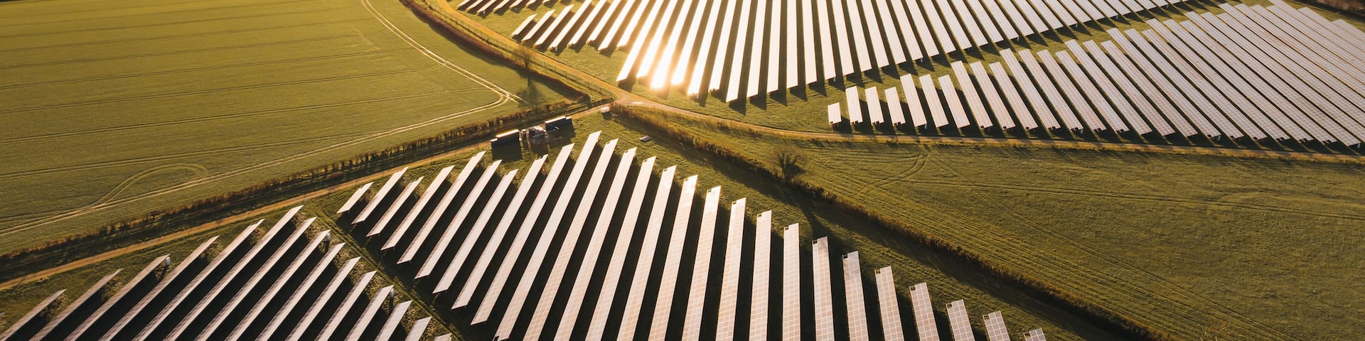An aerial view of a solar farm with rows of solar panels.