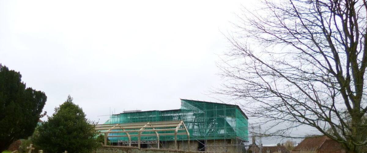 A cemetery with headstones and a building under construction with scaffolding.