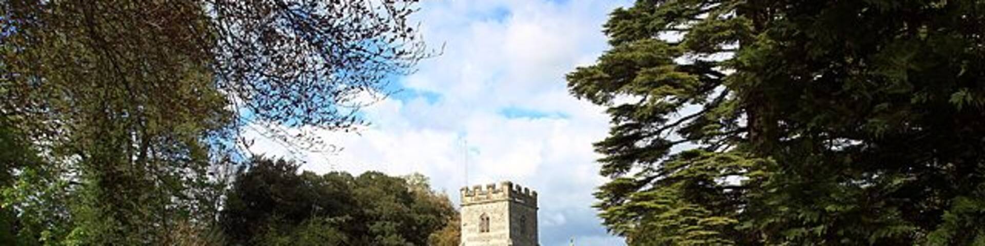 A church with a tower, surrounded by a well-maintained lawn and trees.
