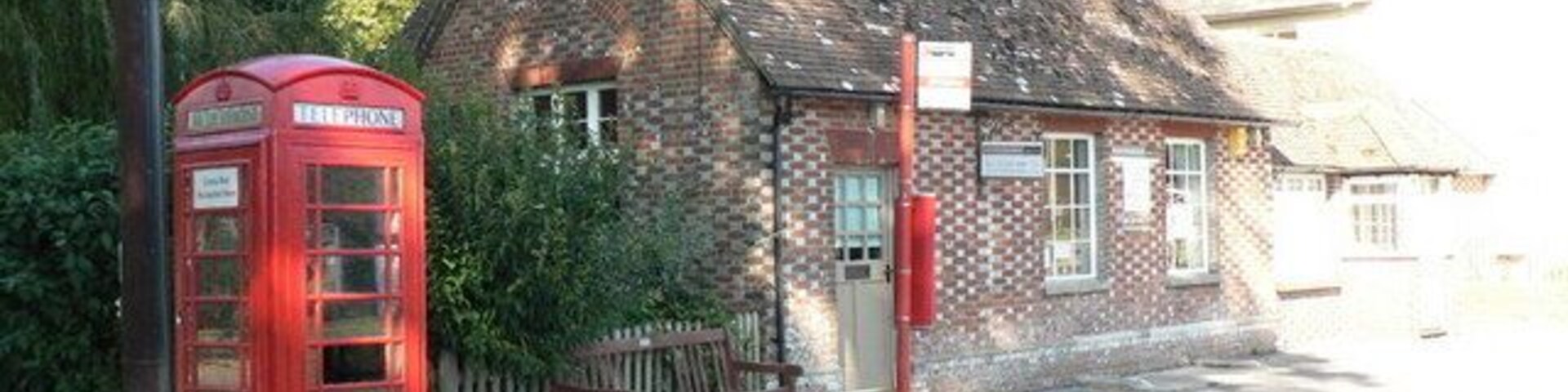 Una cabina telefónica roja, un edificio de ladrillo y una carretera con señal de límite de velocidad.