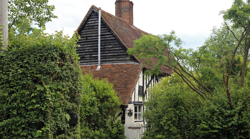 Timber framed cottage with brick chimney and gate, behind hedges and trees at Nazeing, Essex, England