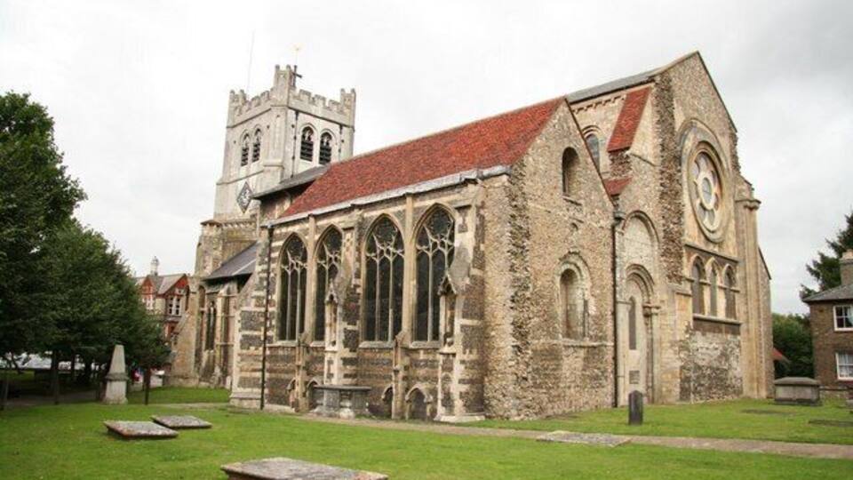A historic church with a prominent clock tower and arched windows.