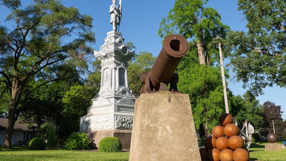 Une statue, un canon et un monument dans un parc.