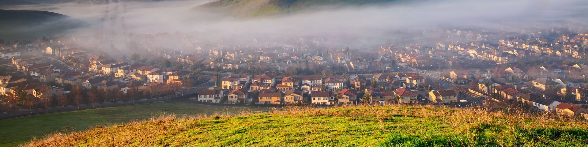 A town nestled between rolling hills and enveloped by a sea of clouds.