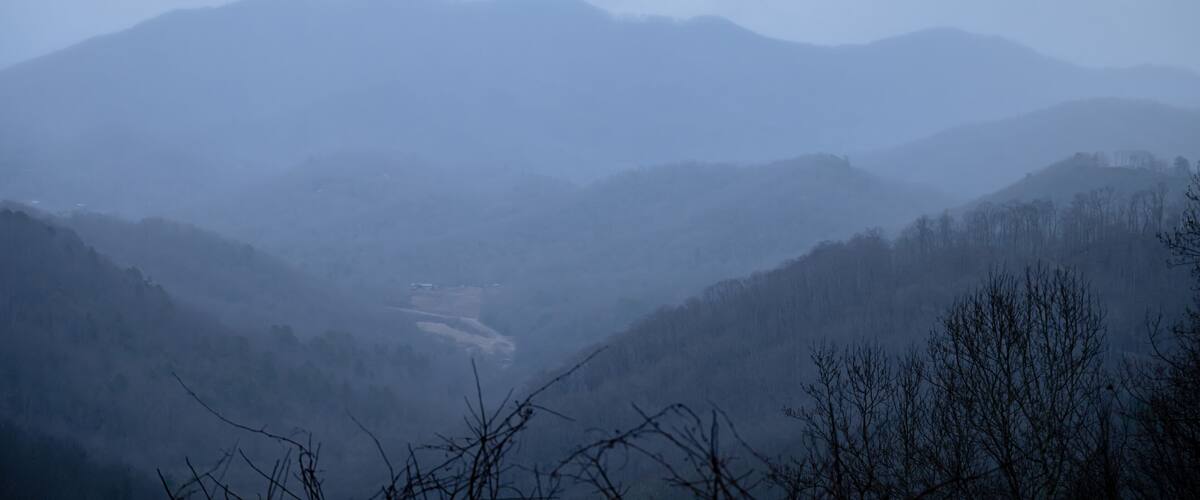 A misty mountain landscape with rolling hills and a valley.