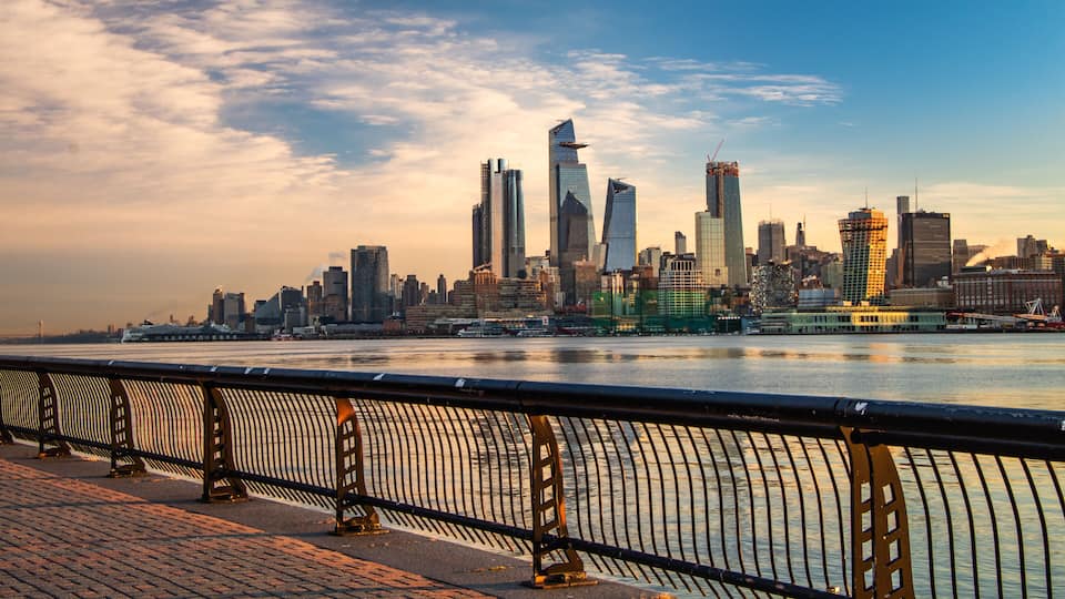 A city skyline with modern skyscrapers, a river, and a bridge in the foreground.