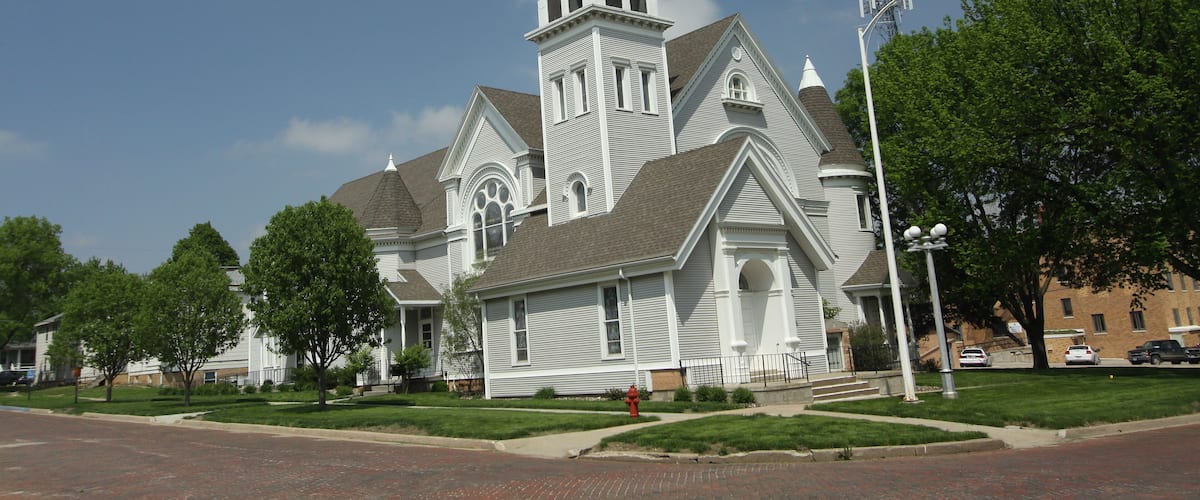 A church with a tall steeple and a brick sidewalk.