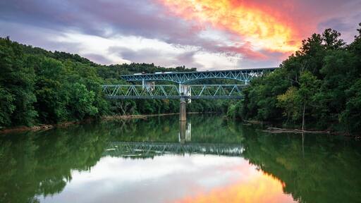 A bridge over a calm river with a sunset reflection.