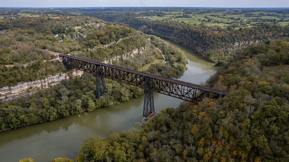 A steel bridge spanning a river in a forested valley.