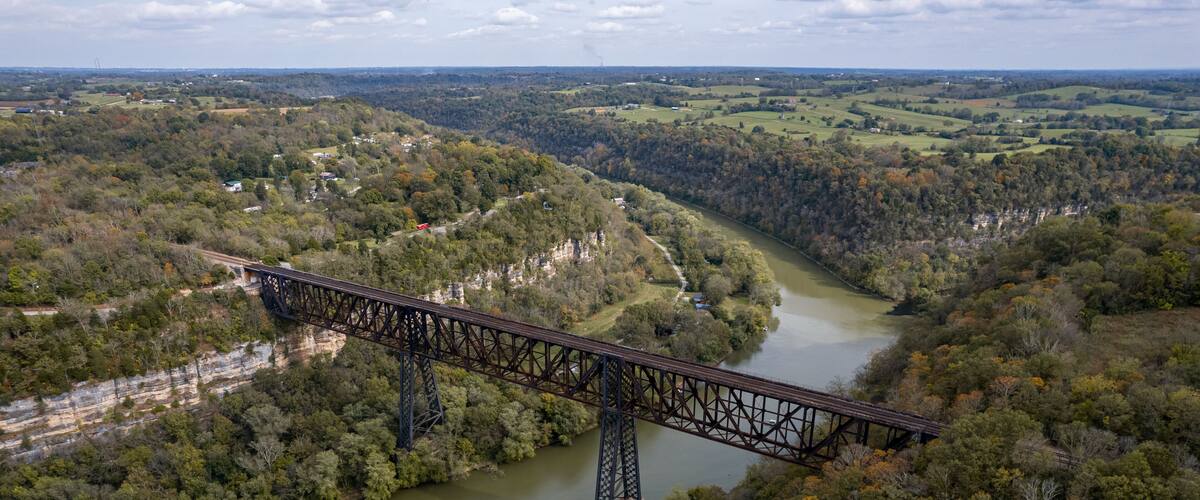 A steel bridge spanning a river in a forested valley.