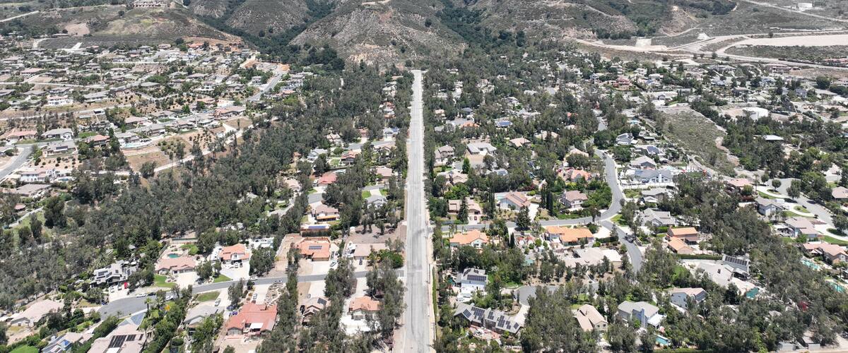 A residential area with houses, roads, and mountains in the background.