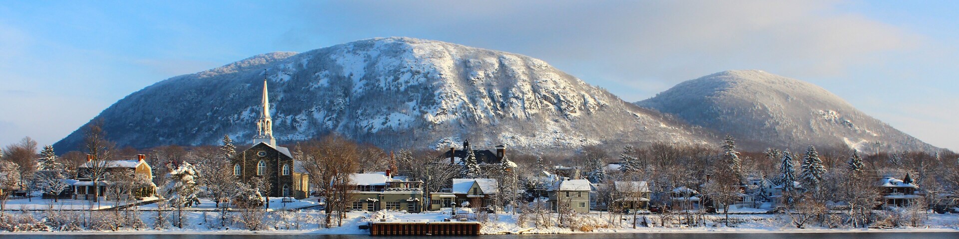 A snow-covered town with a church, houses, and mountains in the background.