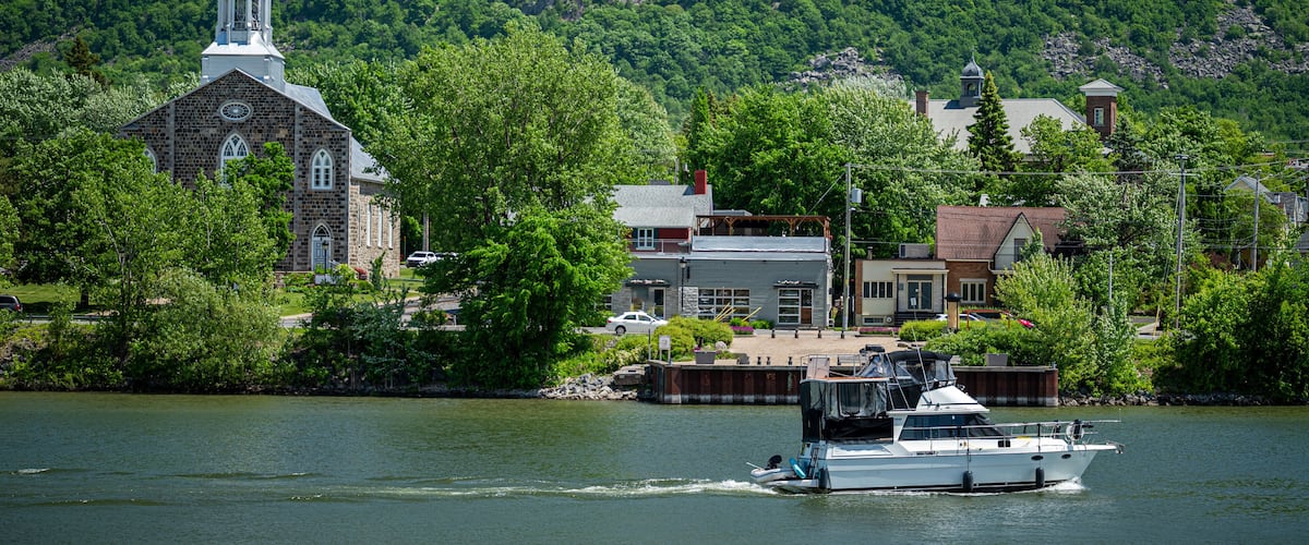 A lake with a boat, a church, and a mountain in the background.