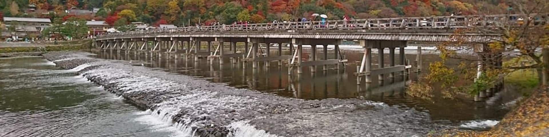 A bridge over a river with autumn foliage in the background.