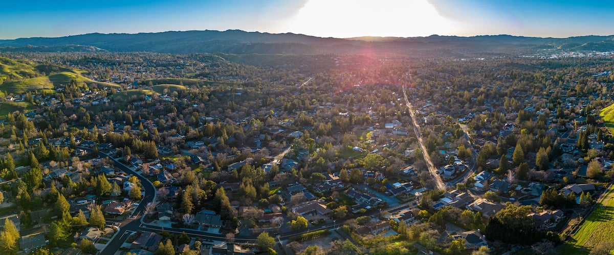 An aerial view of a town nestled in a valley with rolling hills and a river running through it.