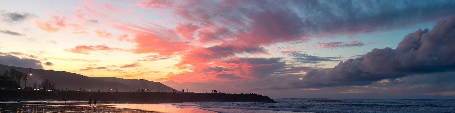 Uma praia ao pôr do sol, com céu colorido e ondas calmas.