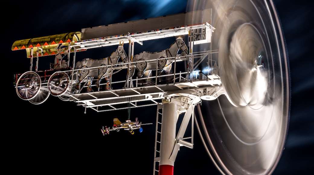 A whirligig spins at night in front of a full moon