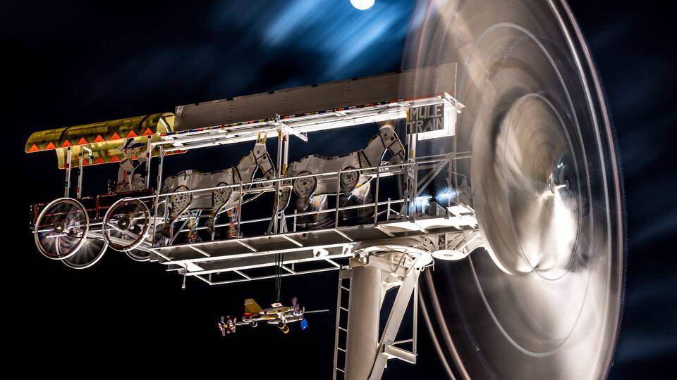 A whirligig spins at night in front of a full moon