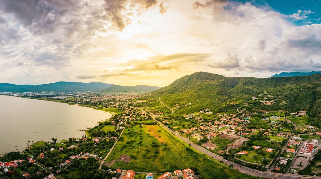 A panorama of mountains and lake with the sunset as background. Clouds and blue sky with trees and colors