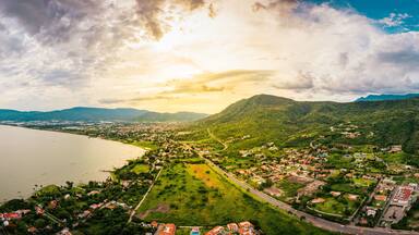 A coastal town with a large lake, surrounded by green hills and mountains.