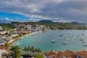 Eine Küstenstadt mit einem Hafen, klarem türkisblauem Wasser und einem Bergpanorama im Hintergrund.