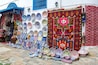Diverse kleurrijk aardewerk en stoffen te zien op een markt.