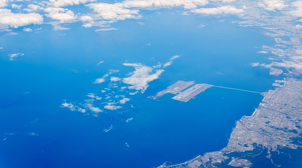 A coastal cityscape with a large body of water, a runway, and scattered clouds.