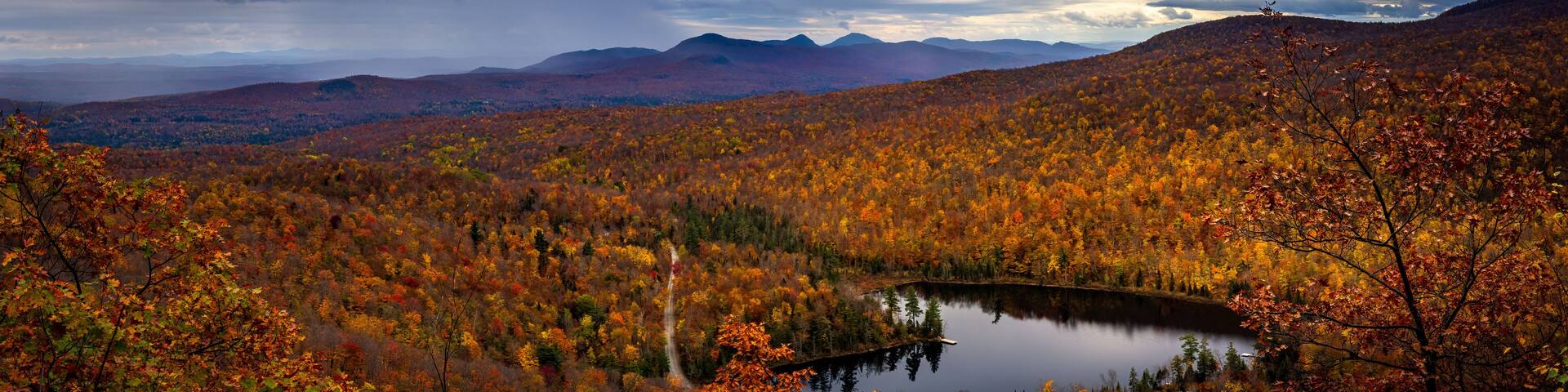 A mountainous landscape with a lake surrounded by autumn-colored trees.