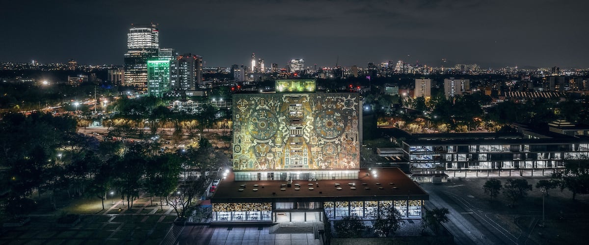 Aerial drone view of Biblioteca Central UNAM, a famous library in Ciudad Universitaria in Mexico City at night, Mexico.