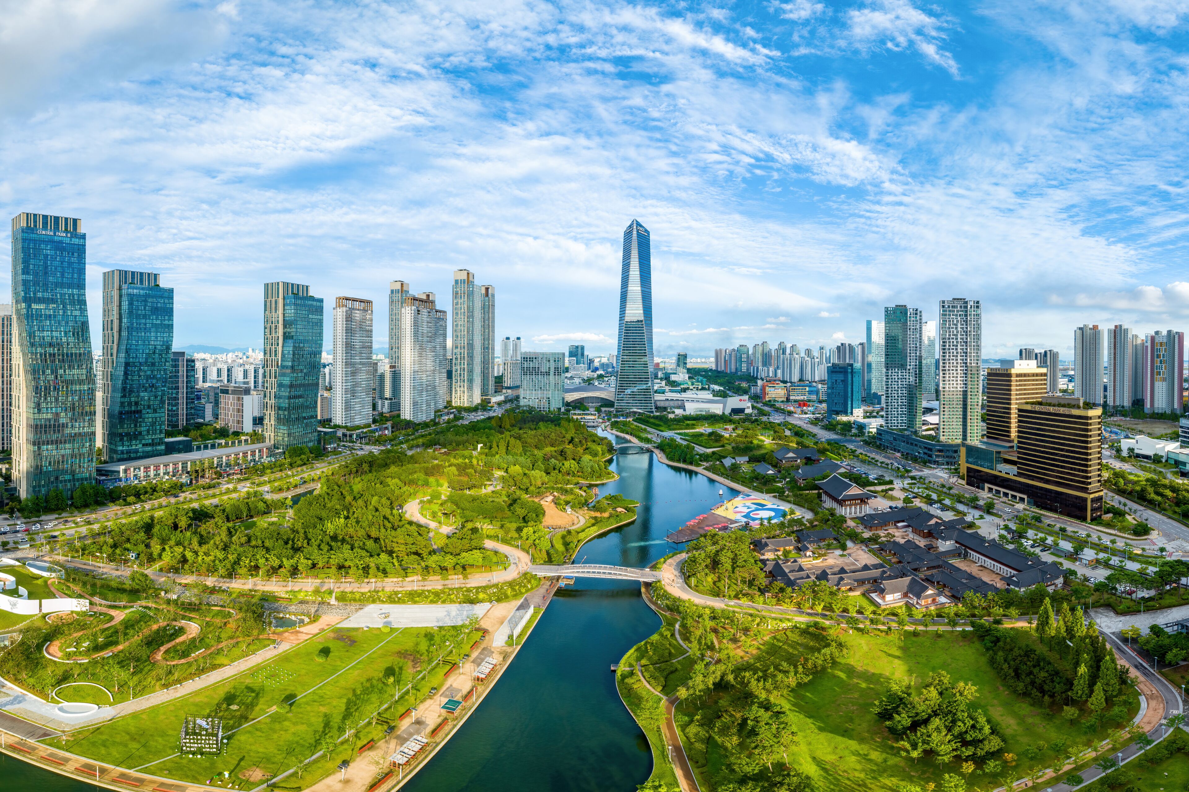 Songdo-dong, Yeonsu-gu, Incheon, South Korea - July 8, 2023: Aerial view of Central Park with canal and Hanok Hotel against apartments and Northeast Asia Trade Tower
