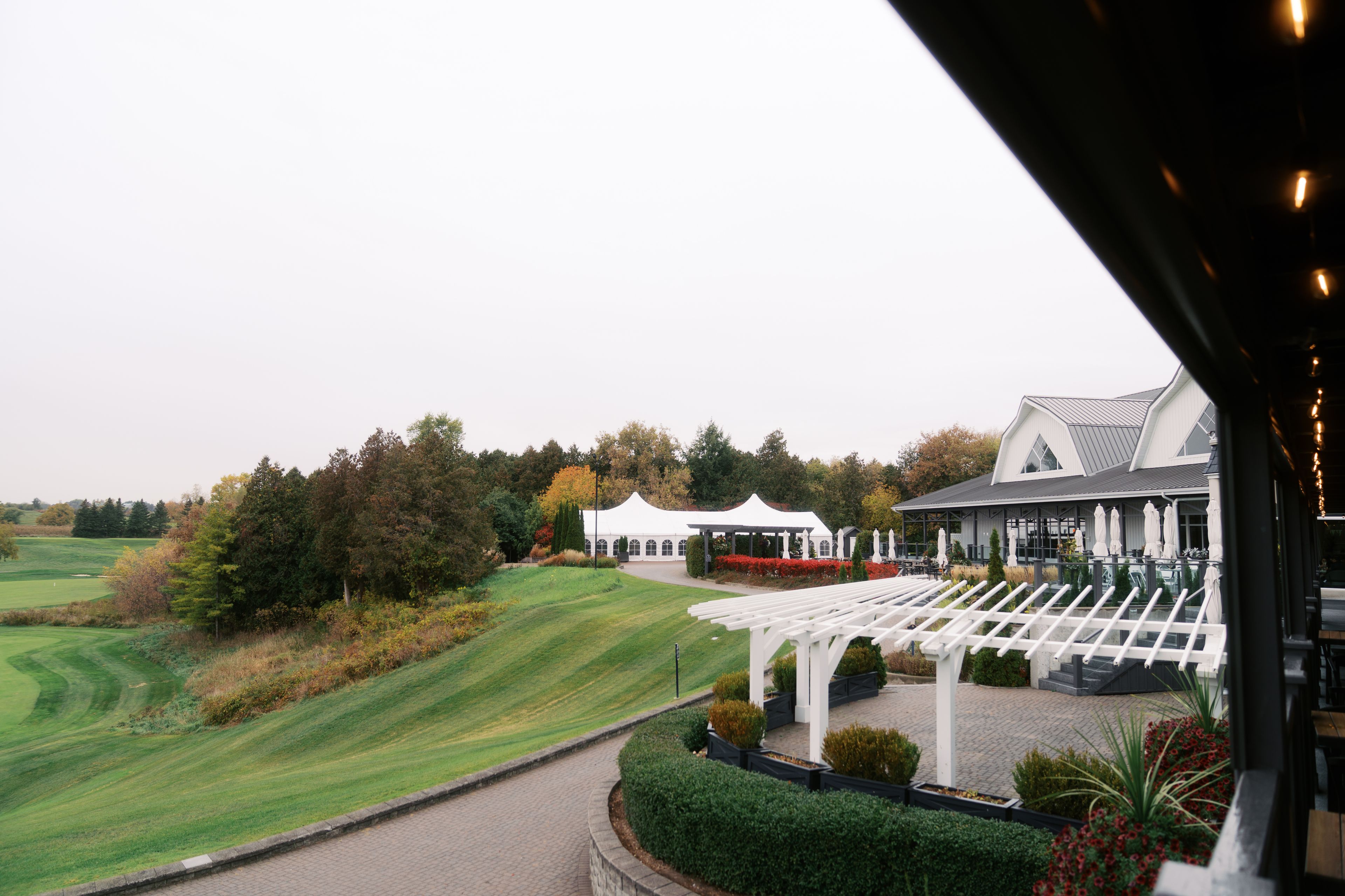 A golf course with a pavilion, a white building with a sloped roof, and a well-maintained lawn.